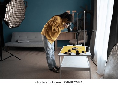 Photographer with SLR camera taking a picture of a product. Shooting beauty products on the table in home studio. Copy space - Shutterstock ID 2284872861