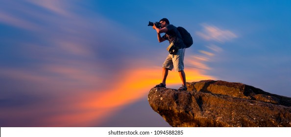 A photographer standing on top of Mountain at sunset with vivid clouds. - Powered by Shutterstock