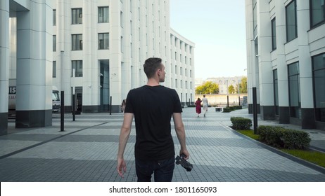 Photographer takes pictures of city's modern architecture. Action. Young man shoots modern architecture with professional camera. Photography is hobby