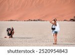 A photographer takes pictures of a young model in the desert - Dead trees in Dead Vlei - Sossusvlei, Namib desert, Namibia