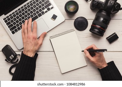 Photographer taking notes while using laptop. Top view on creative designer workplace with photo equipment and computer, timetable planning and self-education concept, copy space
