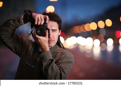 Photographer taking photo with DSLR camera at night. Shallow DOF.