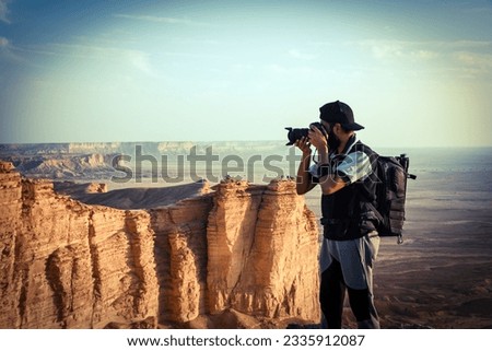 A photographer taking photo from the edge of the world near Riyadh Saudi Arabia.The edge of the world is a term used to describe places that offer a spectacular view of the horizon, where the sky meet