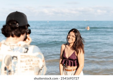 Photographer taking photos of a beautiful smiling woman posing on a beach with ocean and sky in background - Powered by Shutterstock