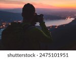 photographer taking picture of Annecy lake in France at twilight, night photography, silhouette of man with backpack and dslr camera