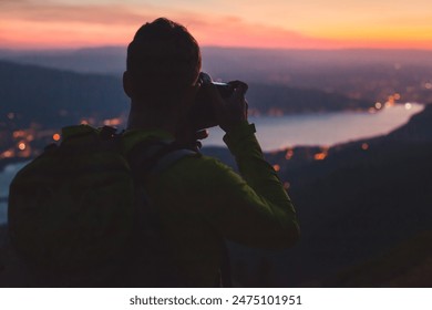 photographer taking picture of Annecy lake in France at twilight, night photography, silhouette of man with backpack and dslr camera