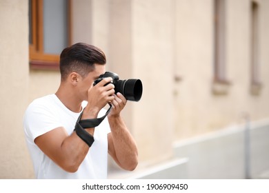 Photographer taking picture with professional camera on city street