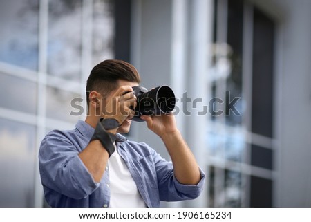 Photographer taking picture with professional camera on city street