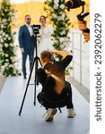 Photographer taking pictures of the bride and groom at the off-site ceremony. Selective focus. Professional videographer and wedding photographer.