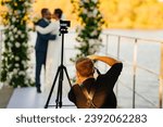 Photographer taking pictures of the bride and groom at the off-site ceremony. Selective focus. Professional videographer and wedding photographer.