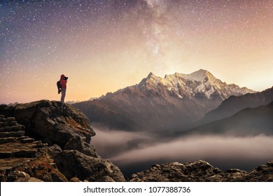 Photographer traveler who take picture of starry sky enjoying sunrise on peak of over snowy mountains in the Himalayas, Langtang, Nepal. Night colorful landscape. Starry sky with mountains at winter.