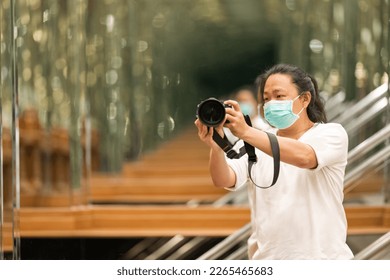 Photographer using camera to taking Self Portrait in the mirror.Photographer with a black SLR camera.