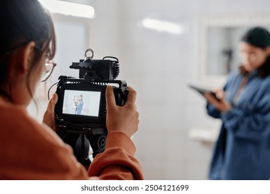 Photographer using professional camera equipment while directing subject in blurry background for photoshoot in indoor setting - Powered by Shutterstock