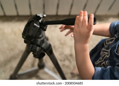 Photographer And Videographer Equipment. Tripod. The Child Is Holding A Tripod. Tripod Adjustment. Hands Are Holding A Tripod.