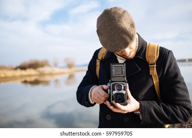 Photographer with vintage photo camera. Bearded man using retro camera outdoor - Powered by Shutterstock