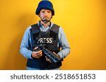 Photographer wearing a helmet and a bulletproof vest with the word "PRESS" on it. He holds a camera in his hands.