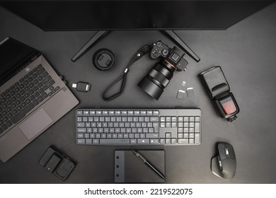 Photographer Work Station On Dark Background With Laptop, Camera, Flash, Lens, Drawing Tablet, Keyboard, Mouse. Top View
