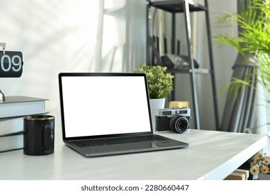 Photographer working desk with laptop, camera, books and coffee cup. Empty screen mobile phone for graphic display montage - Powered by Shutterstock