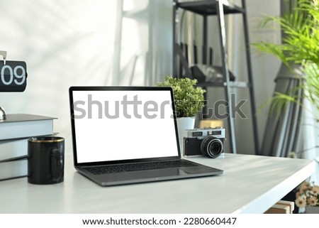 Photographer working desk with laptop, camera, books and coffee cup. Empty screen mobile phone for graphic display montage