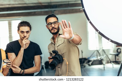 Photographer working with his assistants doing a photo shoot in a studio. Photographer with his team during a photo shoot making adjustments. - Powered by Shutterstock