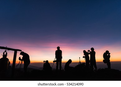 Photographers Silhouettes On Cliff Against Colorful Twilight Sky