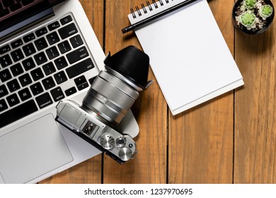 Photographer's table with computer and blank notebook.