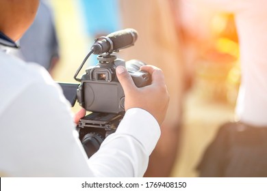 Photographers are using dslr cameras to capture the atmosphere in the morning. The hand is holding the camera with blurred of green background. - Powered by Shutterstock