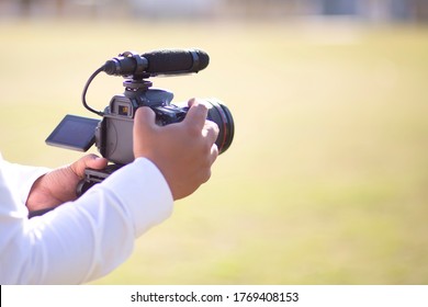 Photographers are using dslr cameras to capture the atmosphere in the morning. The hand is holding the camera with blurred of green background. - Powered by Shutterstock