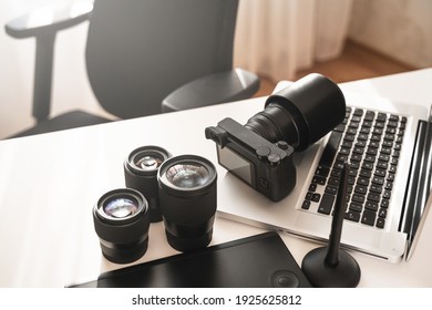 Photographer's workplace with a modern equipment. Mirrorless camera, laptop and prime lenses.