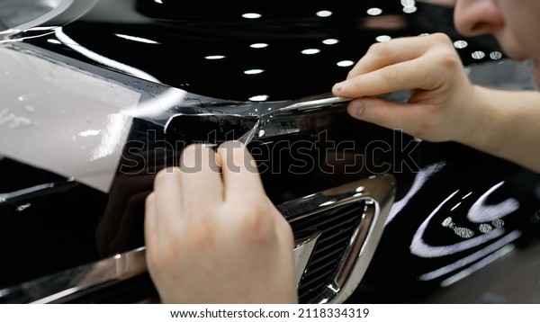 Photographing a car body in\
a car service. Car detailing. The protective film is cut with a\
knife on the car.