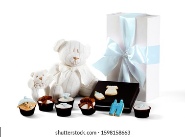 Photography Of Baby Boy Christening Gift Hamper With Teddy Bear, Baby Rattle. Present, Cupcakes And Cookies On White Background