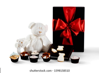 Photography Of Baby Christening Gift Hamper With Present, Teddy Bear, Baby Rattle, Cupcakes And Cookies On White Background