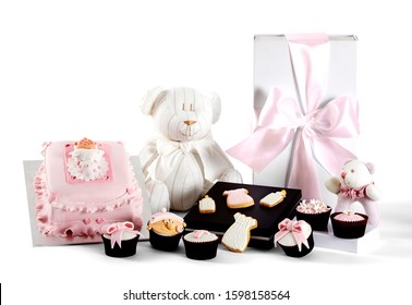 Photography Of Baby Girl Christening Gift Hamper With Cake, Present, Teddy Bear, Baby Rattle, Cupcakes And Cookies On White Background