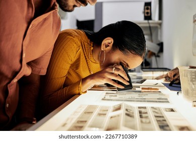 Photography, editing and film negatives for looking, magnifying glass or zoom analysis at photo journalist job. Photographer man, analyse or focus with woman in studio for creative choice in teamwork - Powered by Shutterstock