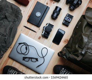 Photography equipment nicely organized on light raw wooden planks background. Travel photographer, work and travel, mobile office concept. Creative freelancer accessories concept.