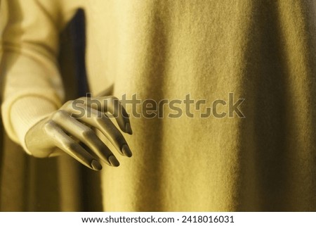 Photography of a female mannequin's hand in the soft yellow light. Close up image. Details in the focus