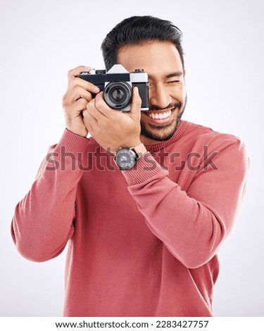 Photography, happy and man with a camera in a studio for creativity or art photoshoot job. Happiness, smile and Indian male photographer taking pictures for paparazzi or the media by white background