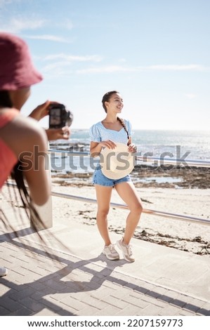 Photography, model and woman with photographer at the beach shooting on a beautiful day outdoors in summer. Smile, happy and young girl at sea as a creative social media influencer enjoying sunshine
