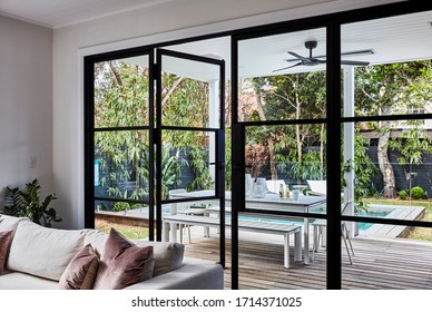 Photography Of A Modern Patio With Outdoor Furniture In A Landscaped Poolside Garden Shot Through The Lounge Room Doors