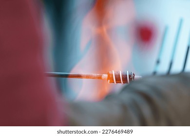 Photography of the process of making beads in the workshop. Glassblower make one bead. Ancient traditional Slavic technique.