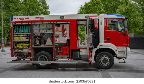 photography of a red firetruck with its doors opened with its equipment on sight during the day and trees in the background 