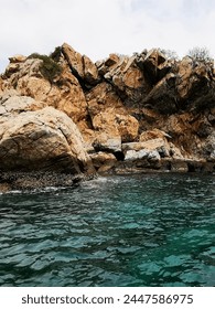 a photography of a rocky cliff with a body of water.