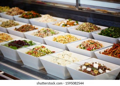 Photography Of A Salad Bar In Glass Display Cabinet In Deli With Various Salads In White Square Bowls