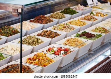 Photography Of A Salad Bar In Glass Display Cabinet In Deli With Various Salads In White Square Bowls