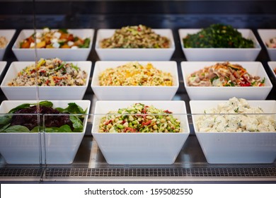 Photography Of A Salad Bar In Glass Display Cabinet In Deli With Various Salads In White Square Bowls