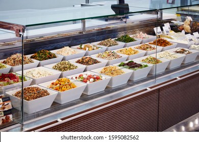 Photography Of A Salad Bar In Glass Display Cabinet In Deli With Various Salads In White Square Bowls