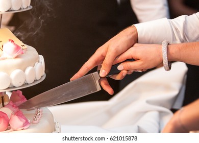 Photography showing the hands of a bride and groom cutting the weddingcake on their wedding day