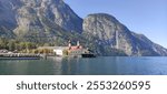 photography of the St. Bartholomew Church on lake Königsee in Germany. the church is on the lake shore, with mountains in the background

