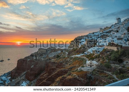A photography of view of Oia, on Santorini island in Greece. The island is surrounded by blue water. Traditional white buildings. Classical greek architecture.