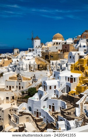 A photography of view of Oia, on Santorini island in Greece. The island is surrounded by blue water. Traditional white buildings. Classical greek architecture.